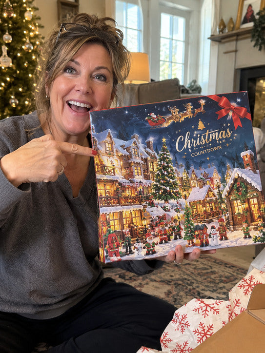 Woman pointing to a blue snowy-village Christmas countdown box.